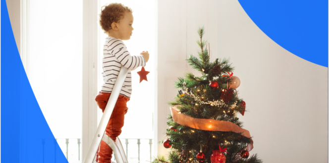Child standing on ladder to hang ornaments on Christmas tree