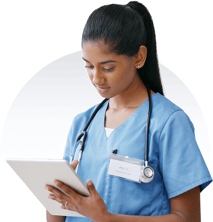 Female healthcare professional in blue scrubs reviewing patient information on a tablet.