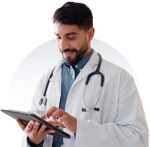 Physician smiles in front of a maple leaf background while looking down at their tablet.